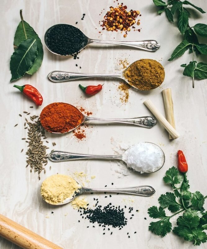 five gray spoons filled with assorted-color powders near chilli